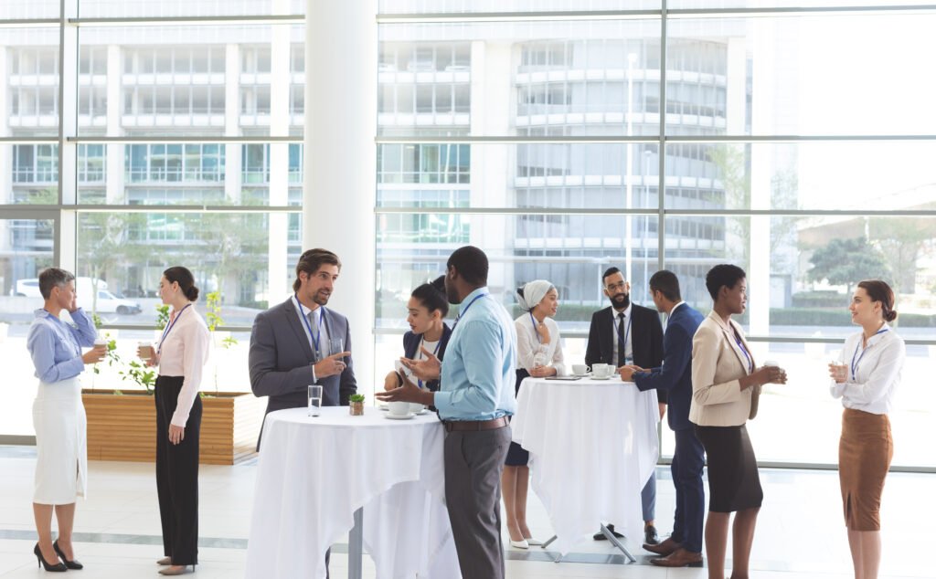 Front view of diverse business people interacting with each other at table after a conference in office lobby